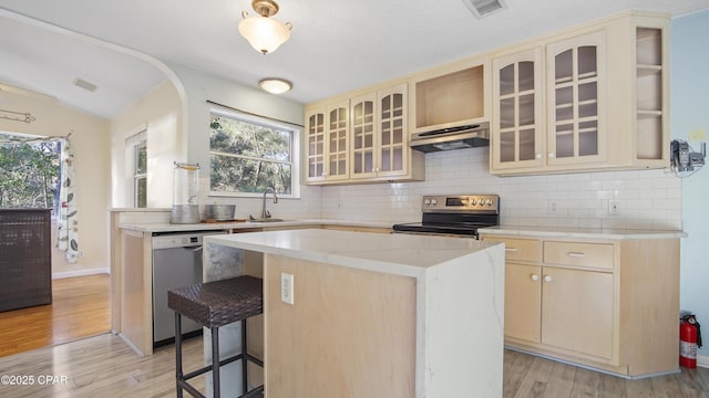 kitchen with a kitchen island, stainless steel range with electric cooktop, light countertops, dishwasher, and glass insert cabinets