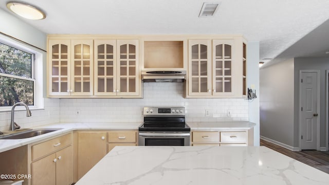 kitchen featuring visible vents, glass insert cabinets, a sink, under cabinet range hood, and stainless steel electric range