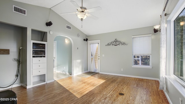 unfurnished room with visible vents, arched walkways, vaulted ceiling, and wood finished floors