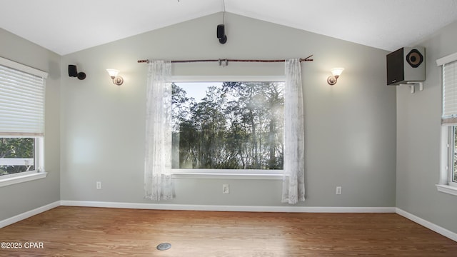 empty room with lofted ceiling, baseboards, and wood finished floors