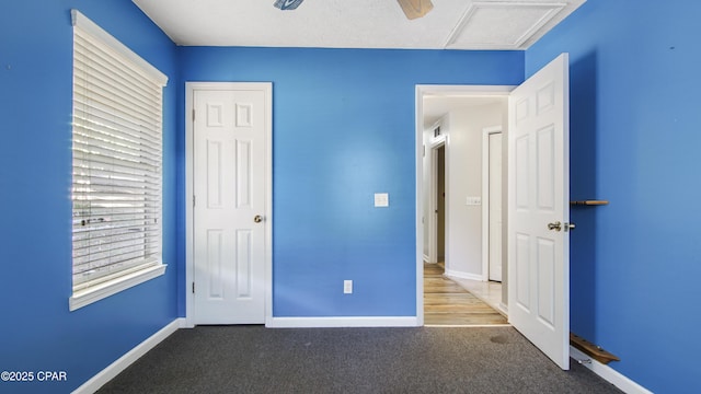 unfurnished bedroom featuring attic access, visible vents, baseboards, a ceiling fan, and carpet flooring