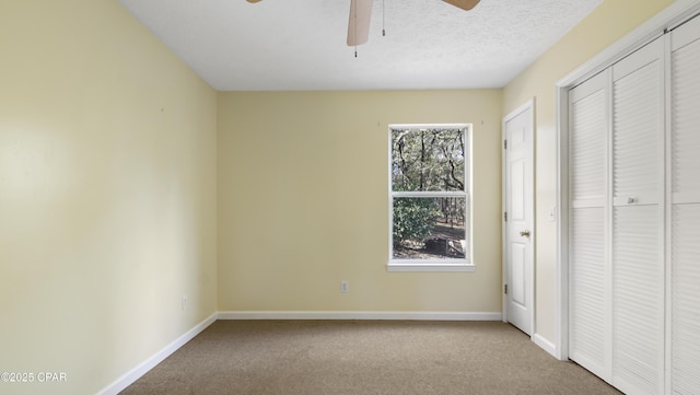 unfurnished bedroom with carpet flooring, ceiling fan, a textured ceiling, and baseboards