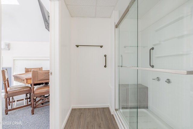 bathroom with walk in shower, wood-type flooring, and a drop ceiling