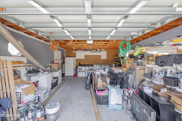 garage with washing machine and clothes dryer and white refrigerator