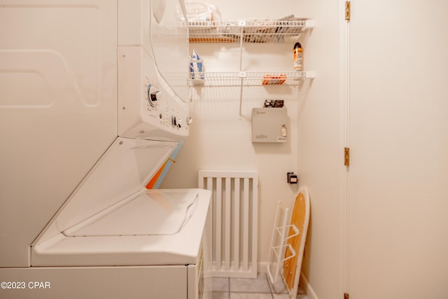 laundry room featuring light tile patterned floors and stacked washing maching and dryer