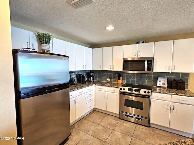 kitchen with decorative backsplash, white cabinetry, light tile patterned flooring, and appliances with stainless steel finishes