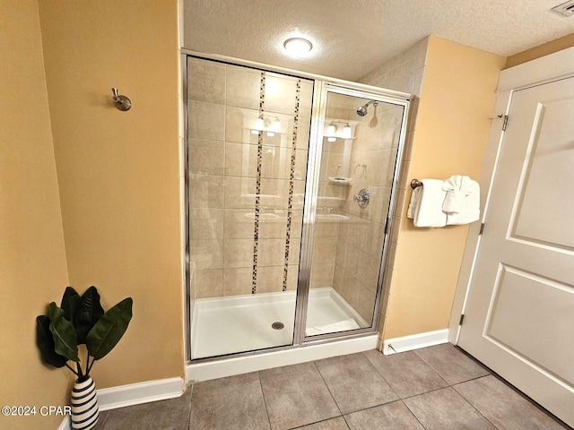 bathroom featuring tile patterned floors, a shower with shower door, and a textured ceiling