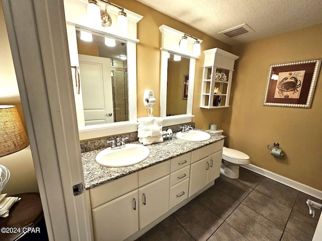 bathroom with tile patterned flooring, a textured ceiling, vanity, and toilet