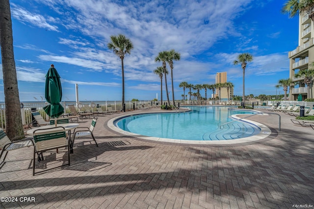 view of swimming pool with a patio area and a water view