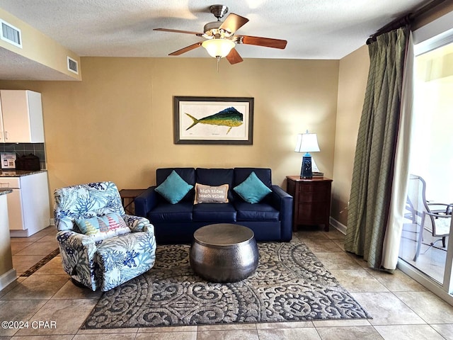 tiled living room with a textured ceiling and ceiling fan