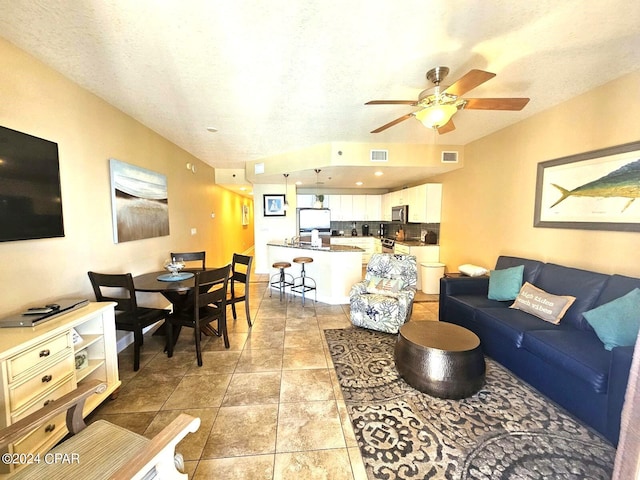 tiled living room with ceiling fan and a textured ceiling