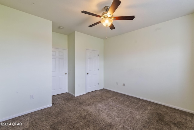 unfurnished bedroom with ceiling fan and dark colored carpet