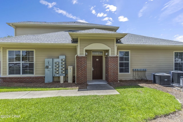 view of front facade with a front yard and central air condition unit