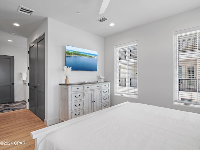 bedroom with wood-type flooring, multiple windows, and ceiling fan