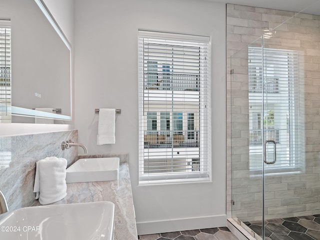 bathroom with a shower with door, double sink, and tile patterned floors