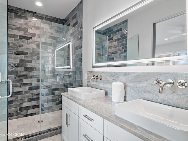 bathroom with ceiling fan, backsplash, vanity, and a shower with shower door