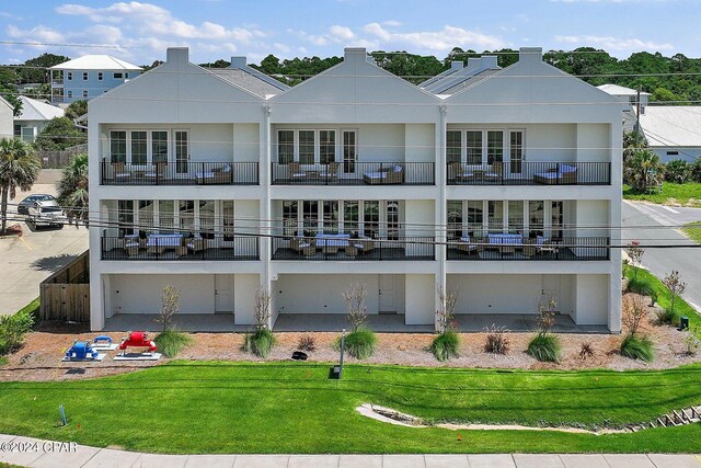 101 Deluna Pl Unit A, Panama City Beach, FL 32413 - back of house with stucco siding, a lawn, and a balcony