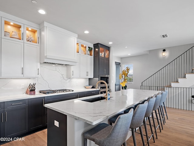 kitchen featuring light wood-type flooring, a center island with sink, sink, and stainless steel appliances