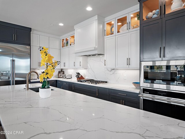 101 Deluna Pl Unit A, Panama City Beach, FL 32413 - kitchen with built in appliances, backsplash, light stone counters, and a sink