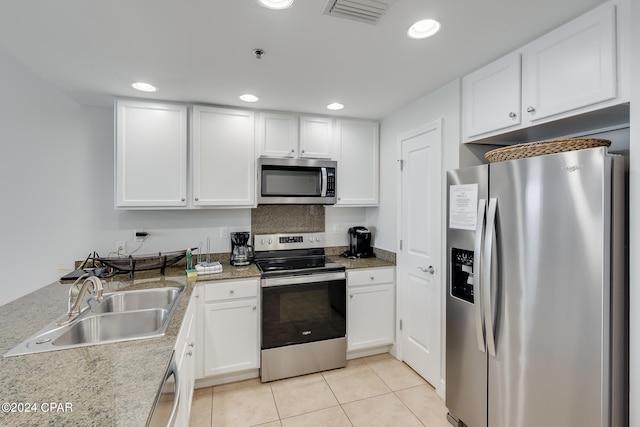 kitchen featuring light stone countertops, sink, light tile patterned floors, white cabinets, and appliances with stainless steel finishes