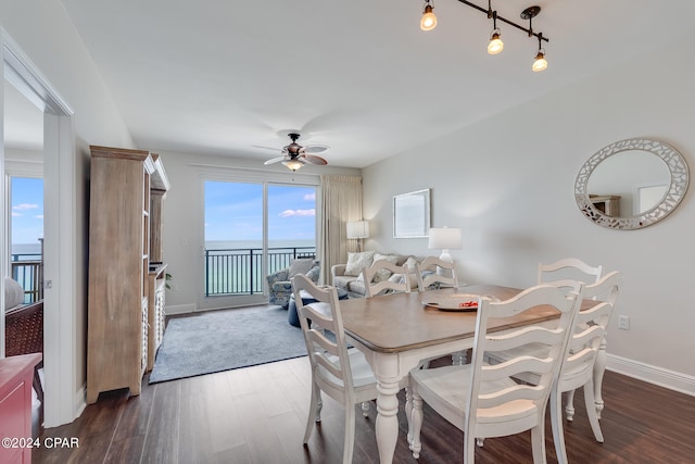 dining room featuring a water view, a wealth of natural light, dark wood-type flooring, and ceiling fan