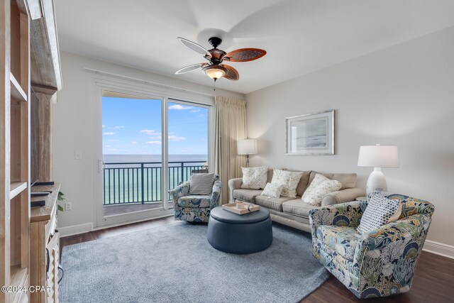 living room with ceiling fan, a water view, and dark wood-type flooring