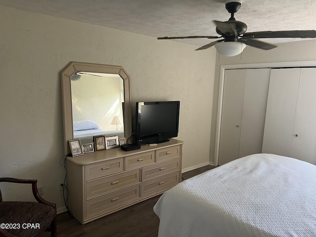 bedroom featuring a textured ceiling, a textured wall, dark wood-style flooring, a ceiling fan, and a closet