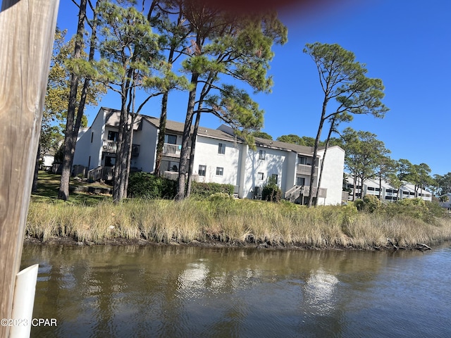 back of property featuring a water view, a residential view, and stucco siding