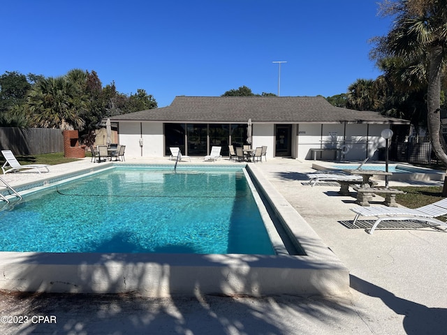 community pool with a patio and fence