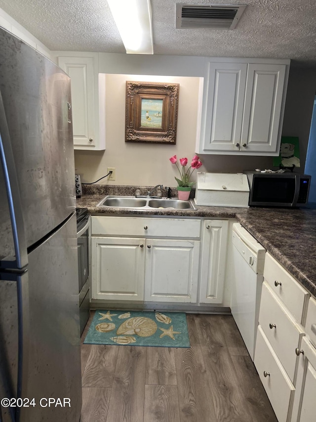 kitchen with stainless steel appliances, dark wood-style flooring, a sink, visible vents, and white cabinetry