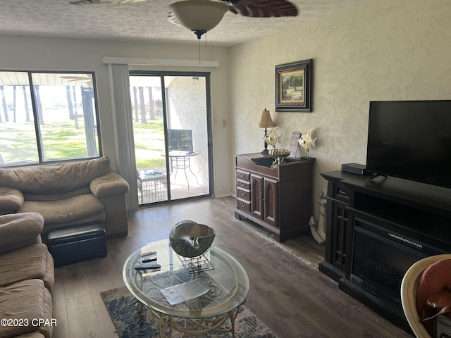 living room with ceiling fan, a textured ceiling, and wood finished floors