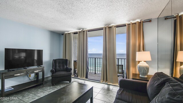 living room featuring light tile patterned flooring, a water view, and a textured ceiling