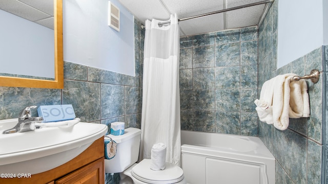 full bathroom featuring tile walls, shower / bath combo with shower curtain, toilet, and vanity