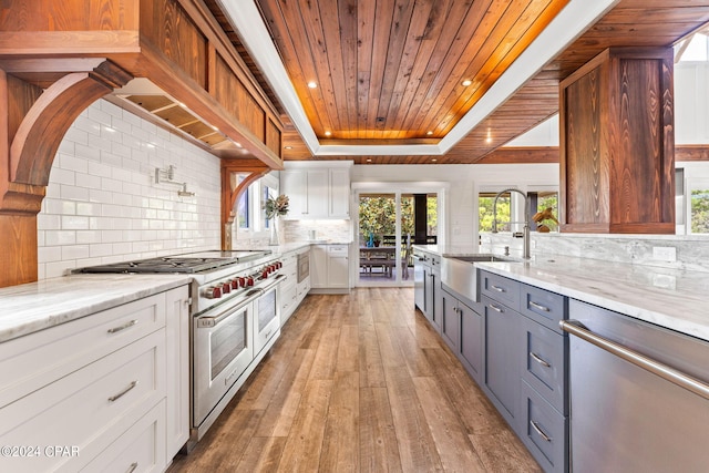 kitchen with light hardwood / wood-style floors, sink, white cabinets, stainless steel appliances, and a raised ceiling