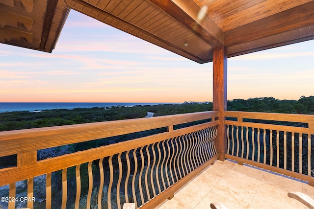 balcony at dusk featuring a water view