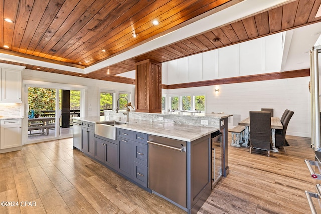 kitchen with a healthy amount of sunlight, sink, light hardwood / wood-style flooring, and white cabinets