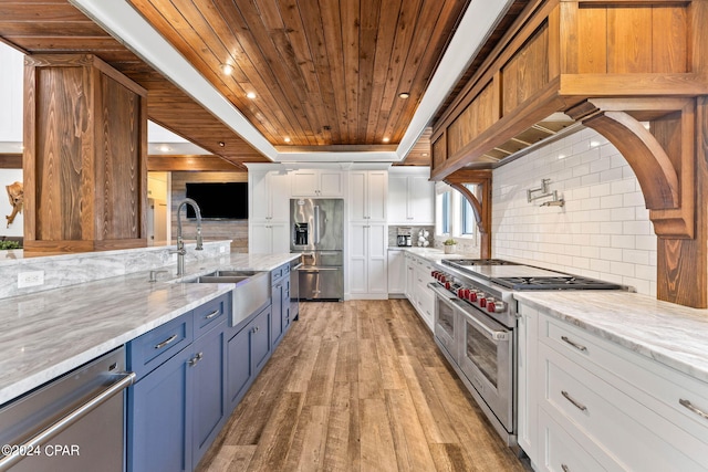 kitchen with light wood-type flooring, sink, white cabinetry, appliances with stainless steel finishes, and light stone countertops