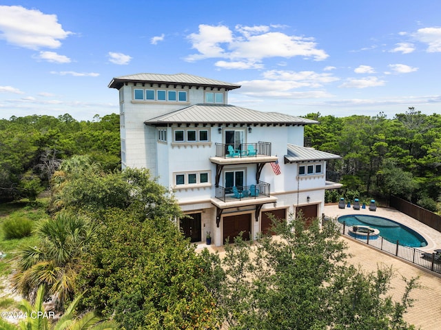 rear view of house featuring a balcony and a fenced in pool