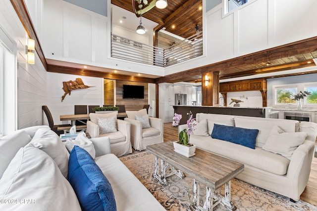 living room with a towering ceiling, wooden ceiling, and light wood-type flooring