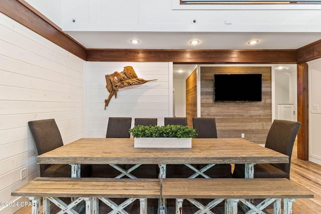 dining space featuring light wood-type flooring and wood walls