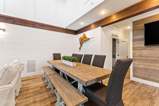 dining area featuring light wood-type flooring and wood walls