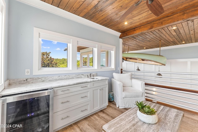 kitchen featuring wood ceiling, wine cooler, light stone countertops, beamed ceiling, and light hardwood / wood-style flooring