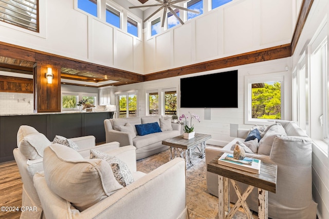 living room with light hardwood / wood-style floors, a towering ceiling, and ceiling fan