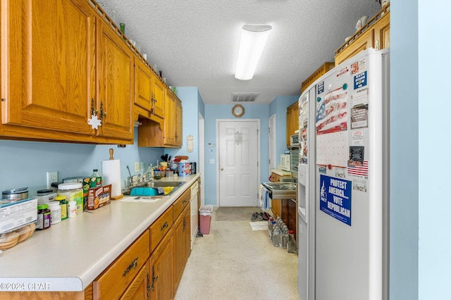 kitchen featuring white fridge with ice dispenser, a textured ceiling, light colored carpet, and sink