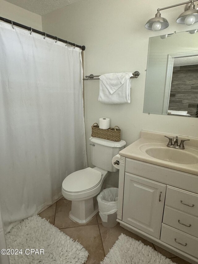 bathroom with tile patterned flooring, toilet, vanity, and a textured ceiling