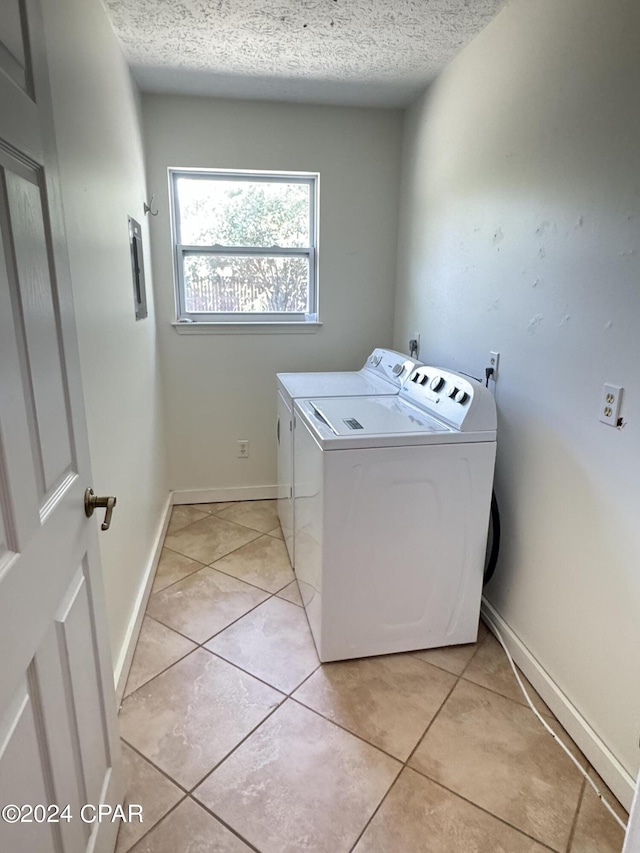 laundry area with washing machine and dryer, light tile patterned floors, and a textured ceiling