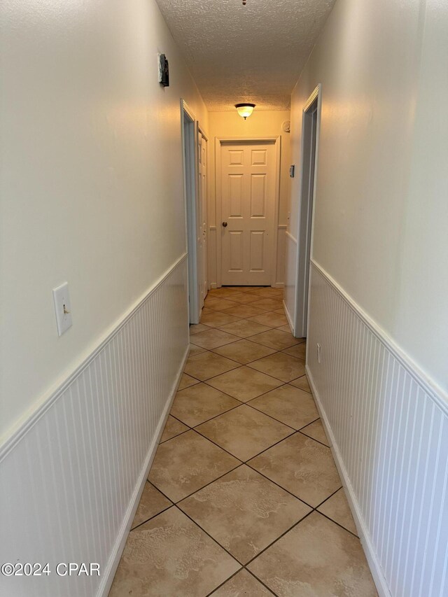 hall featuring a textured ceiling and light tile patterned floors