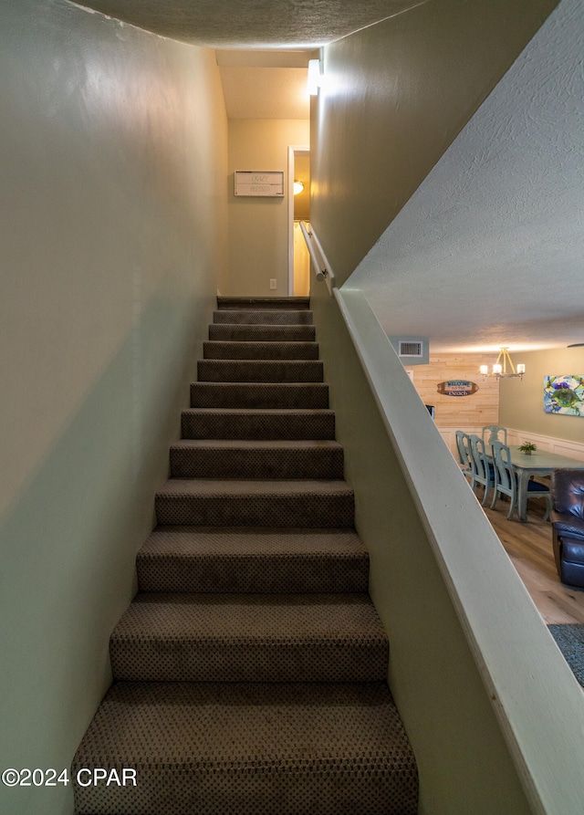 stairs featuring a textured ceiling