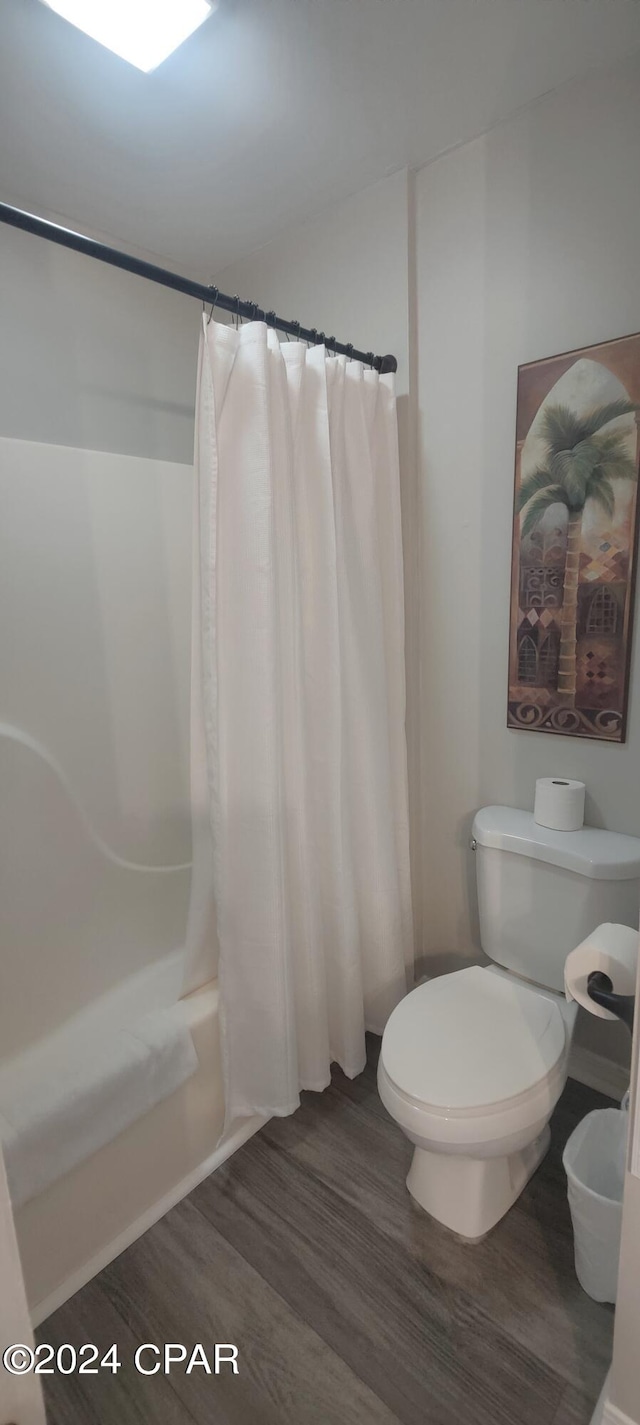 bathroom with shower / bath combo with shower curtain, toilet, and hardwood / wood-style floors