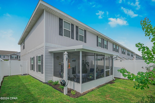 back of property with a sunroom and a lawn